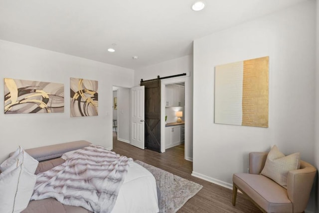 bedroom with dark hardwood / wood-style flooring and a barn door