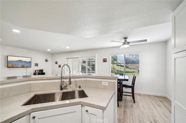 kitchen featuring white cabinetry, sink, a textured ceiling, and light hardwood / wood-style floors