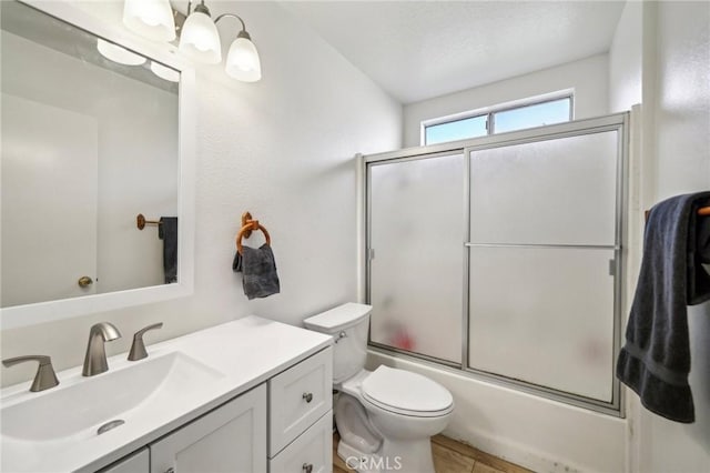 full bathroom featuring vanity, bath / shower combo with glass door, and toilet