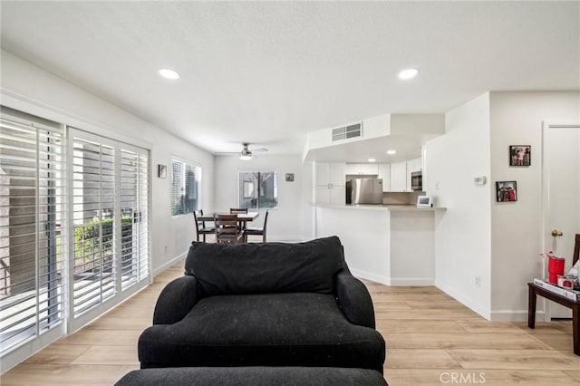 living room with light hardwood / wood-style floors and ceiling fan