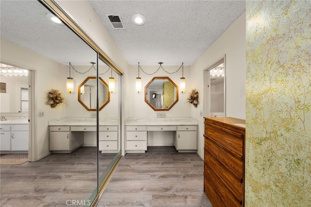 bathroom featuring hardwood / wood-style flooring, vanity, and a textured ceiling