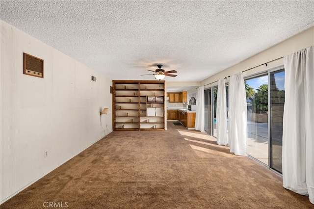 unfurnished living room with ceiling fan, light carpet, and a textured ceiling