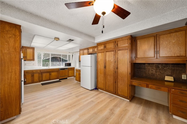 kitchen with light hardwood / wood-style flooring, dishwasher, built in desk, a textured ceiling, and white fridge