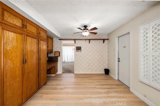 interior space with ceiling fan, light hardwood / wood-style flooring, and a textured ceiling