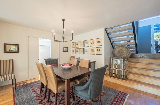 dining space with hardwood / wood-style floors and a chandelier