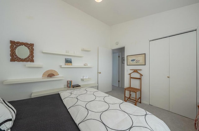 bedroom with vaulted ceiling, light colored carpet, and a closet