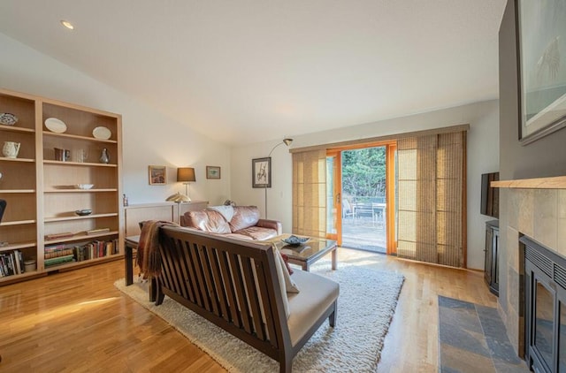 bedroom featuring lofted ceiling, light wood-type flooring, access to exterior, and a fireplace