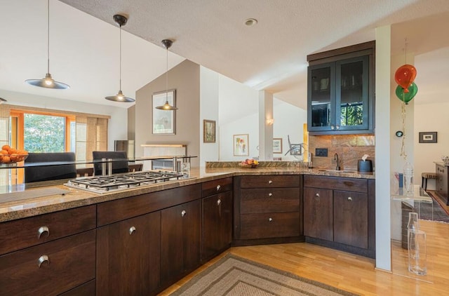 kitchen with sink, decorative light fixtures, light stone countertops, and stainless steel gas stovetop