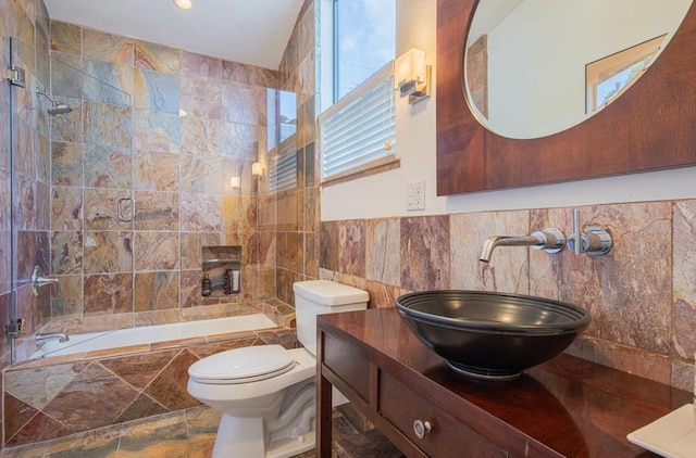 full bathroom with tile walls, vanity, toilet, and combined bath / shower with glass door