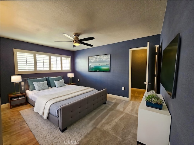 bedroom with ceiling fan, hardwood / wood-style floors, and a textured ceiling