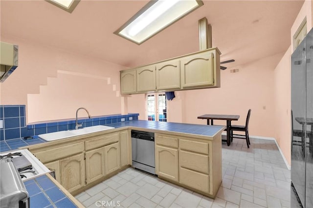 kitchen featuring sink, tile countertops, stainless steel dishwasher, kitchen peninsula, and backsplash