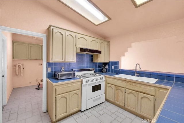 kitchen with vaulted ceiling, tile countertops, tasteful backsplash, sink, and white range with gas cooktop