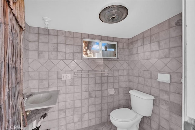 bathroom with tile walls, sink, and toilet