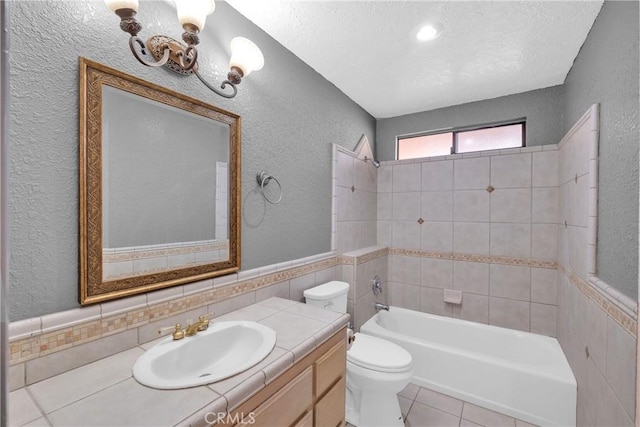 full bathroom with tile patterned flooring, tile walls, tiled shower / bath combo, vanity, and toilet