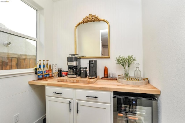 bar with wine cooler, wooden counters, and white cabinets