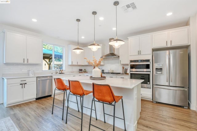 kitchen featuring stainless steel appliances, a kitchen island, pendant lighting, and white cabinets