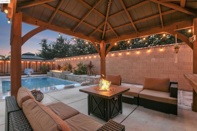 patio terrace at dusk featuring a gazebo, an outdoor living space with a fire pit, and grilling area