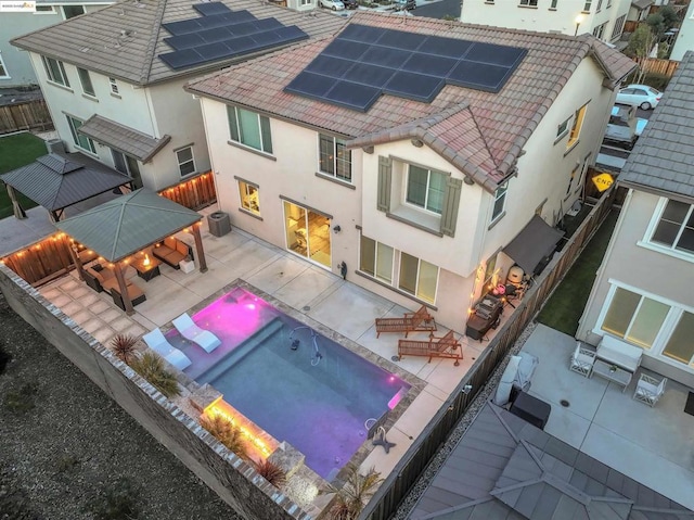 back of property with a gazebo, a patio, and solar panels