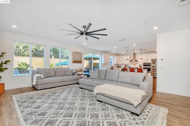 living room with ceiling fan and light hardwood / wood-style flooring