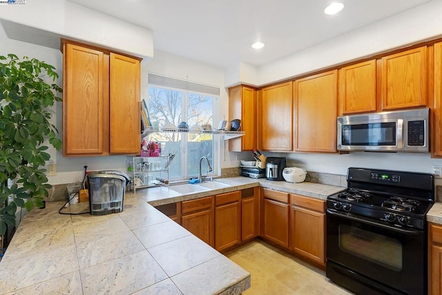 kitchen with tile countertops, black gas stove, and sink