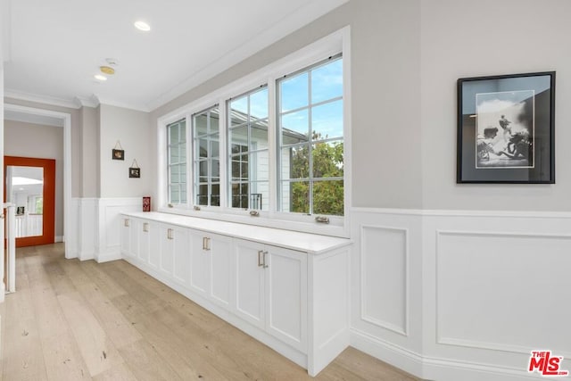 bar featuring white cabinetry, crown molding, and light hardwood / wood-style flooring