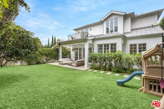 rear view of house featuring a patio area, a balcony, a lawn, an outdoor hangout area, and a playground