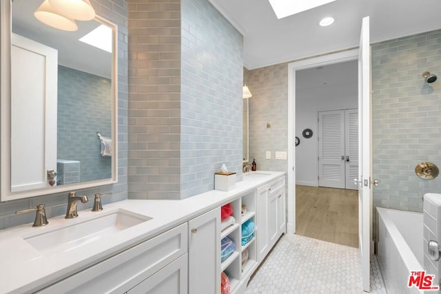 bathroom featuring a bath, vanity, tile patterned flooring, and tile walls