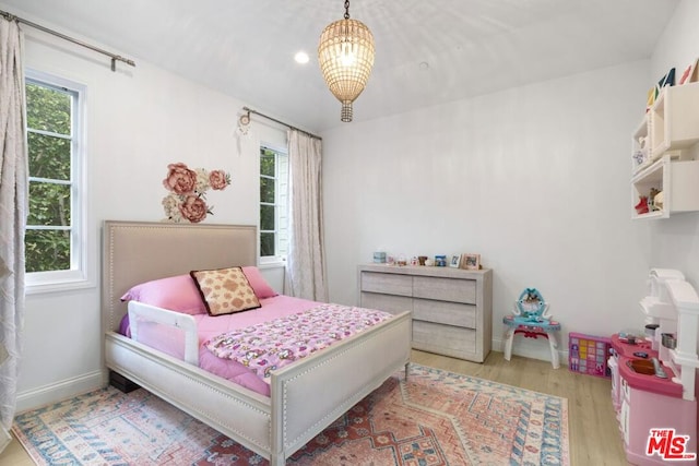 bedroom featuring an inviting chandelier and light wood-type flooring