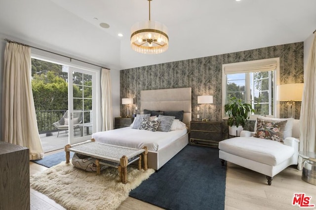 bedroom featuring lofted ceiling, light wood-type flooring, access to outside, and an inviting chandelier