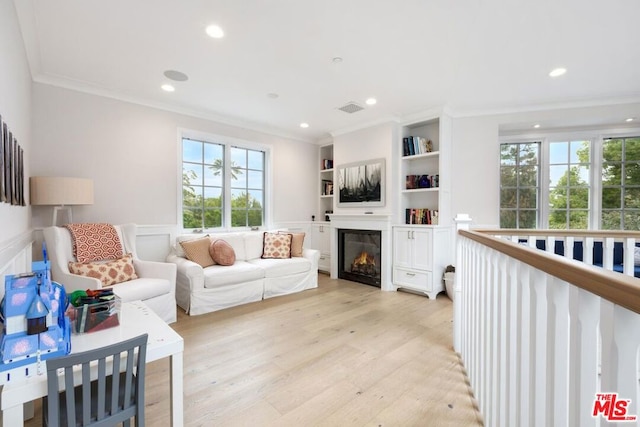 living room with crown molding, built in features, and light hardwood / wood-style floors