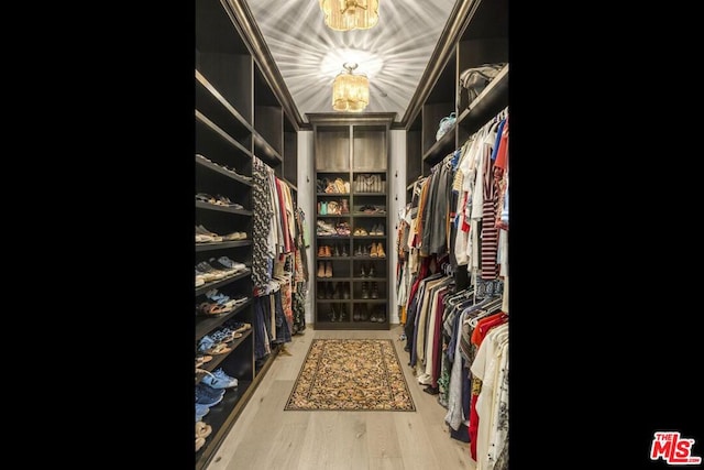 walk in closet with hardwood / wood-style flooring and a notable chandelier