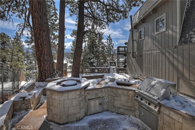 snow covered patio featuring grilling area and exterior kitchen