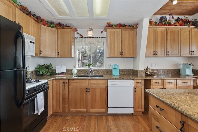 kitchen featuring light stone countertops, sink, light hardwood / wood-style floors, and black appliances