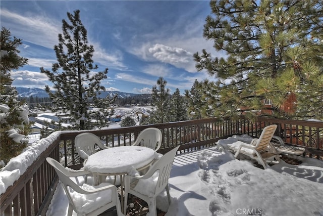 snow covered deck with a mountain view