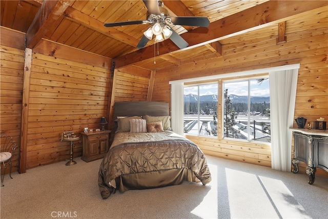 carpeted bedroom featuring vaulted ceiling with beams, wood ceiling, wood walls, a mountain view, and ceiling fan