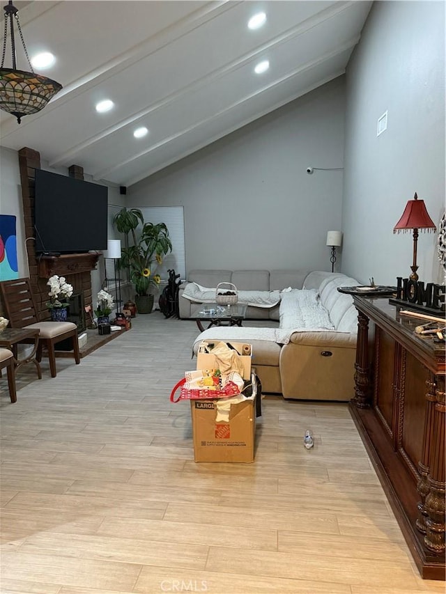 living room featuring a large fireplace, light hardwood / wood-style floors, and lofted ceiling with beams