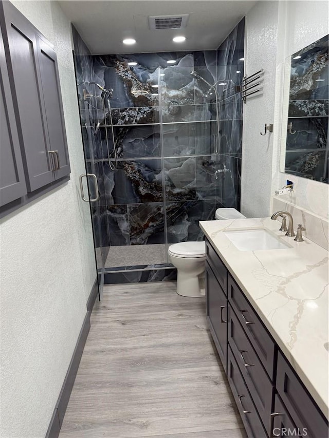 bathroom with toilet, hardwood / wood-style floors, vanity, and walk in shower