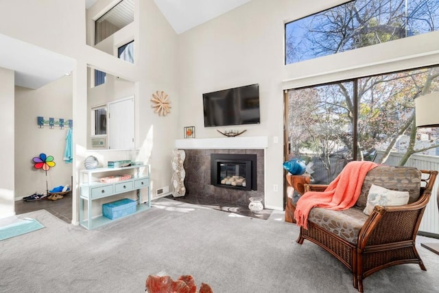 carpeted living room with a towering ceiling and a fireplace