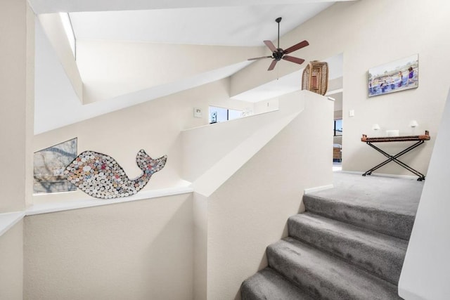 stairway with ceiling fan and lofted ceiling