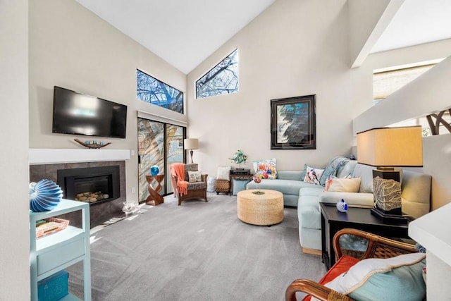 carpeted living room featuring a tiled fireplace and high vaulted ceiling