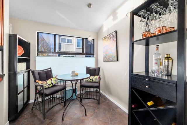 dining area featuring lofted ceiling and dark tile patterned flooring