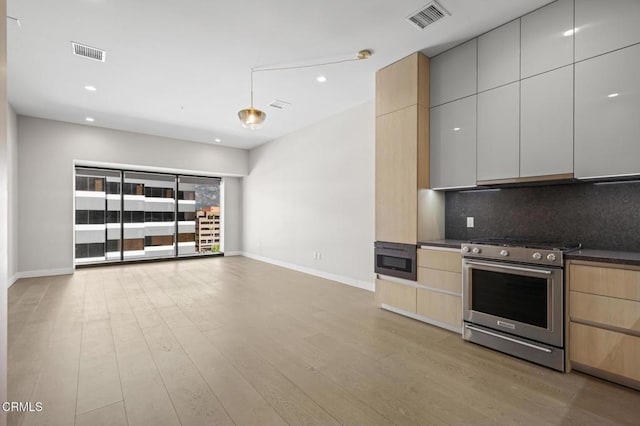 kitchen with tasteful backsplash, appliances with stainless steel finishes, light brown cabinetry, and light hardwood / wood-style flooring