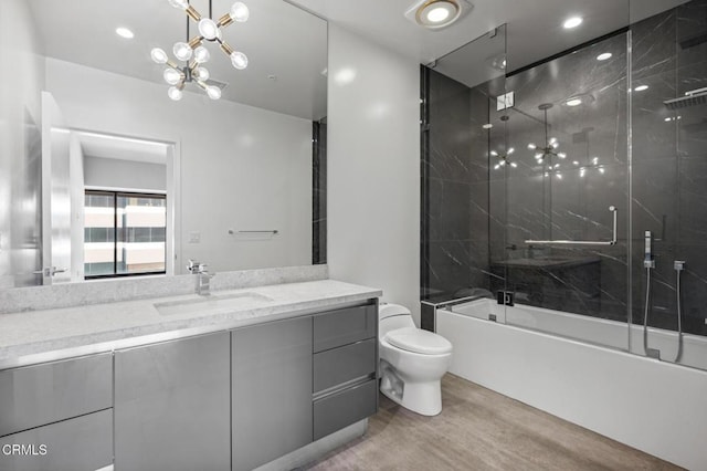 full bathroom featuring enclosed tub / shower combo, vanity, and toilet