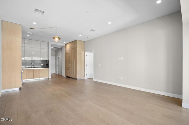 unfurnished living room featuring sink and light hardwood / wood-style flooring