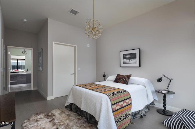 bedroom featuring connected bathroom, dark hardwood / wood-style floors, and a chandelier