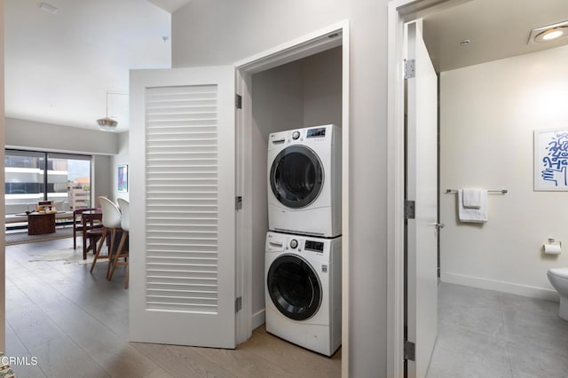 laundry room with stacked washer / drying machine and light hardwood / wood-style floors