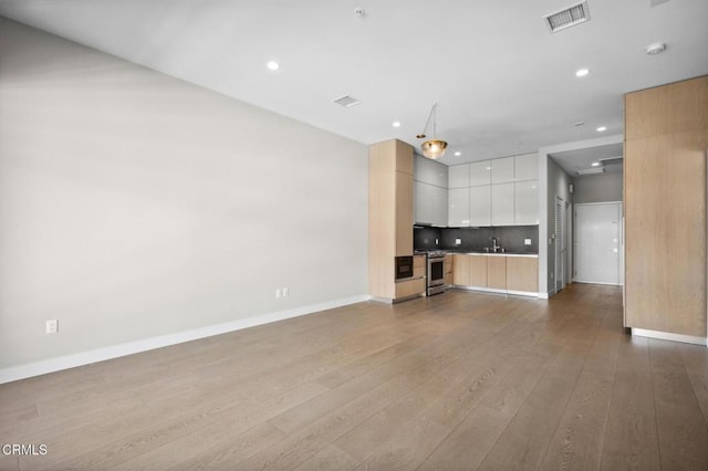 unfurnished living room with wood-type flooring and sink