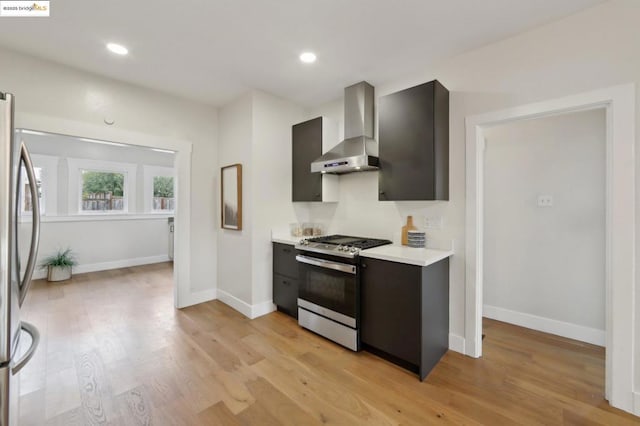 kitchen with stainless steel appliances, light hardwood / wood-style floors, and wall chimney range hood