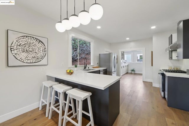 kitchen featuring pendant lighting, sink, a breakfast bar area, kitchen peninsula, and stainless steel appliances