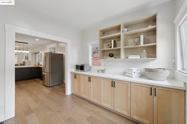 kitchen featuring appliances with stainless steel finishes, decorative light fixtures, light hardwood / wood-style flooring, and light brown cabinets